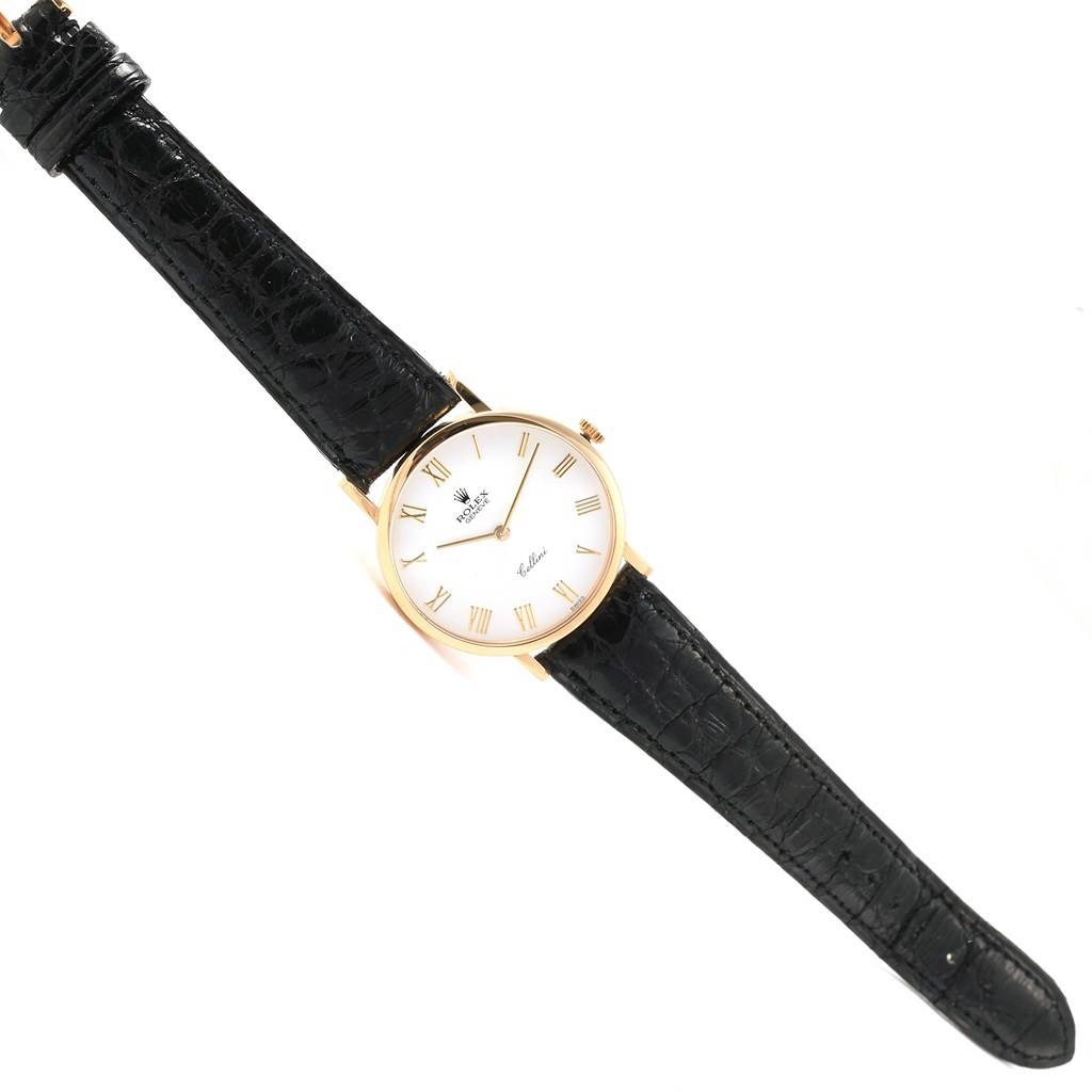The image shows a Rolex Cellini 5112 Yellow Gold White Dial 5112 Yellow Gold White Dial watch from a top-down angle, featuring its round dial, black leather strap, and gold case.