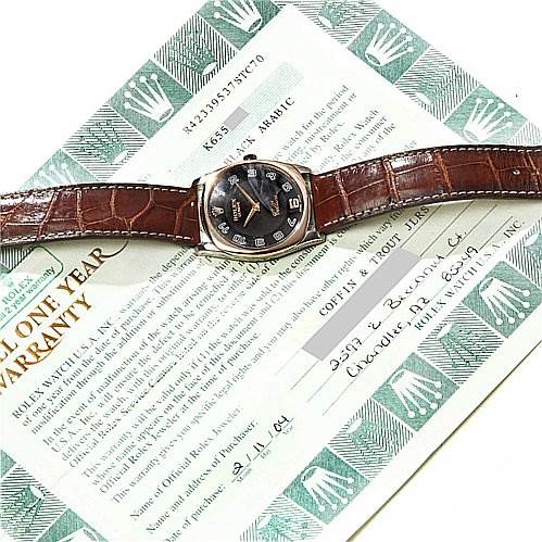 The image shows a Rolex Cellini 4233 White Gold Black Dial 4233 White Gold Black Dial watch with a brown leather strap, displayed on top of its warranty documents.