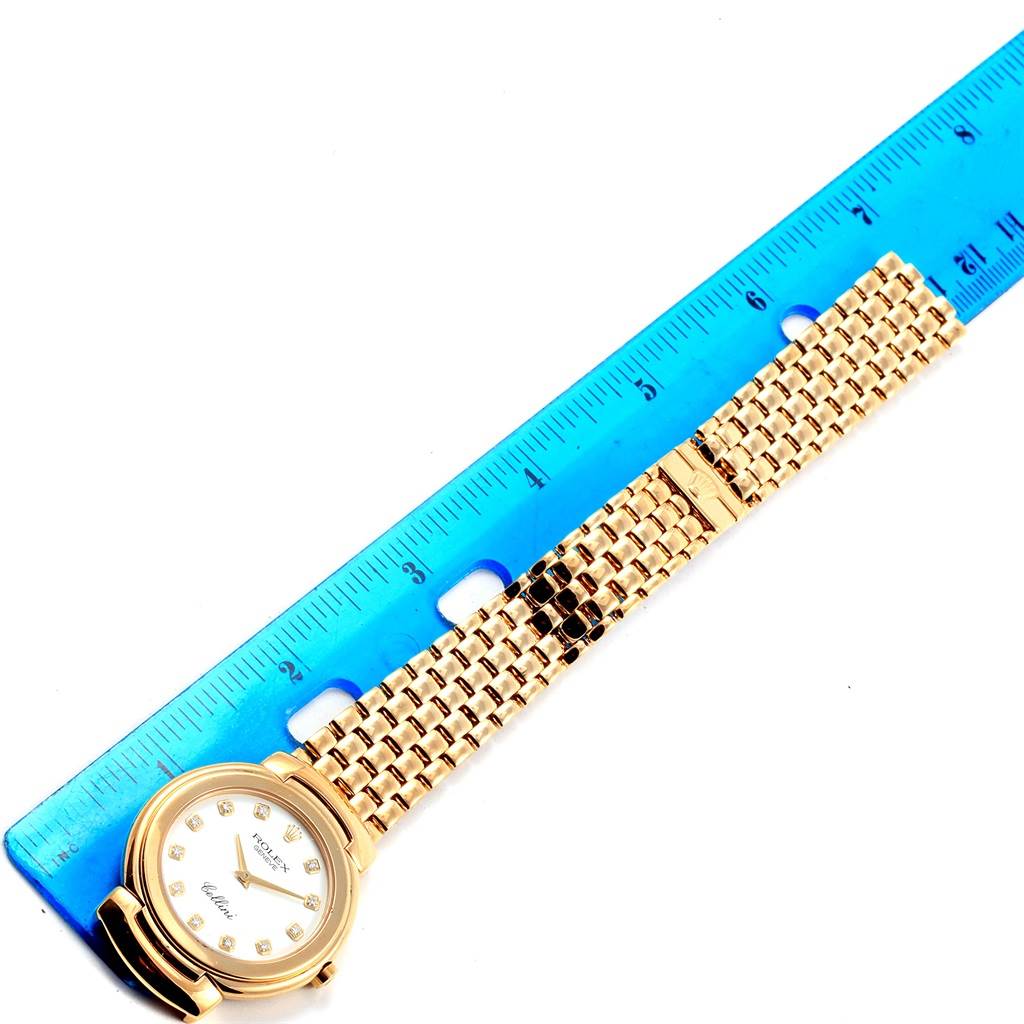 The Rolex Cellini 6622 Women
s Yellow Gold White Dial 6622 Women
s Yellow Gold White Dial watch is shown from a top-down angle next to a blue ruler, highlighting its gold bracelet and round face.