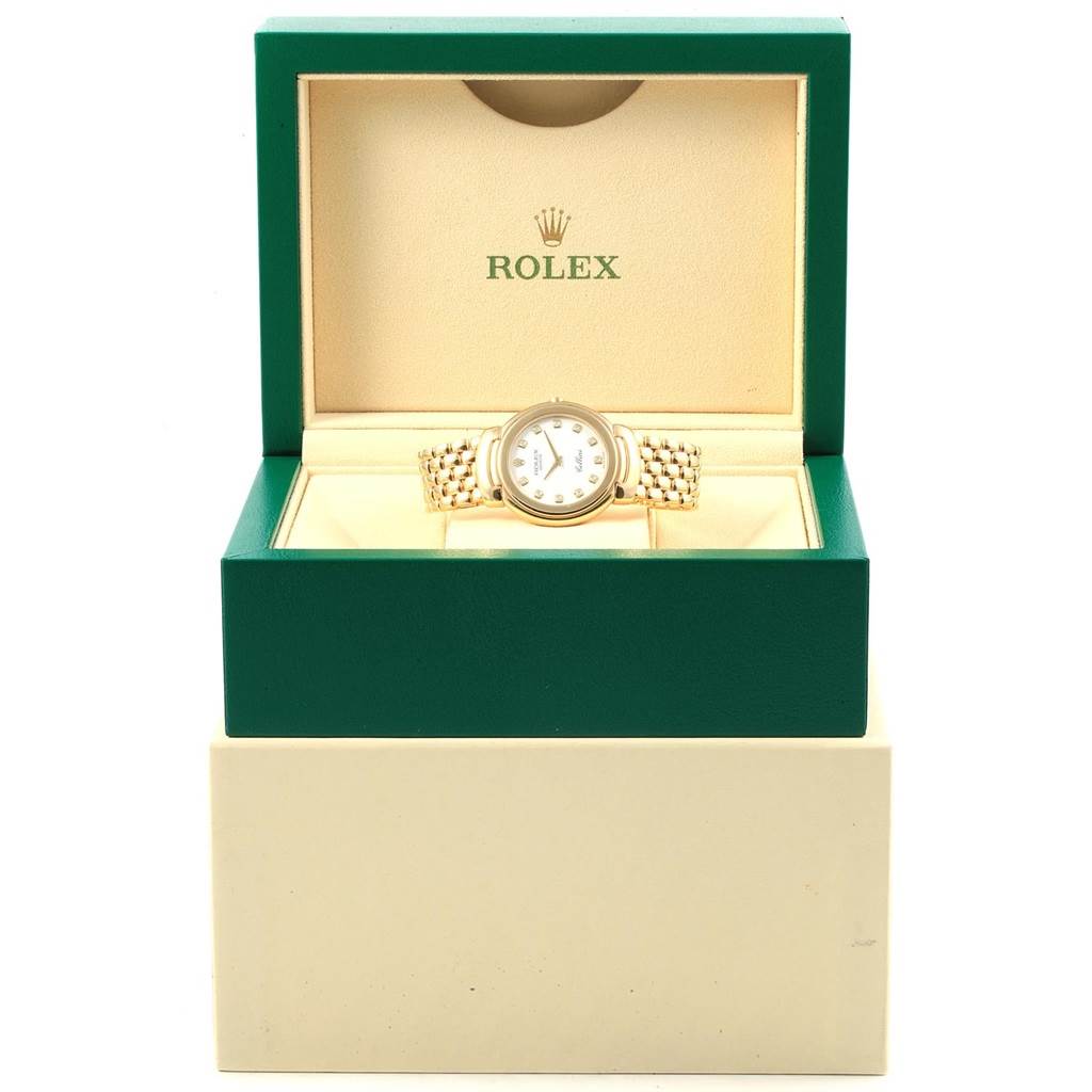 The Rolex Cellini 6622 Women
s Yellow Gold White Dial 6622 Women
s Yellow Gold White Dial watch is shown from the front, inside an open green and beige box with both the watch face and band visible.