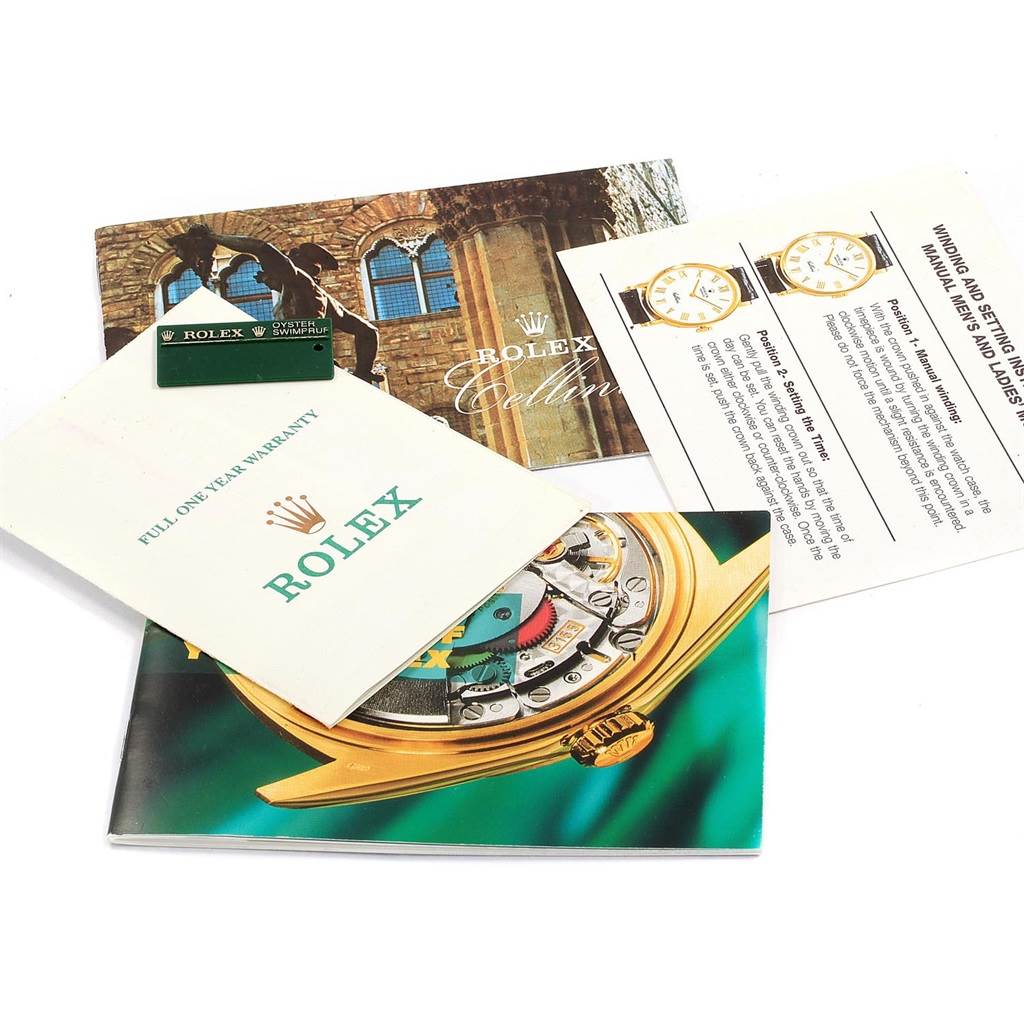 The image shows booklets and warranty cards for a Rolex Cellini 5116 Men's White Gold Black Dial 5116 Men's White Gold Black Dial model, displaying various watch information and branding.