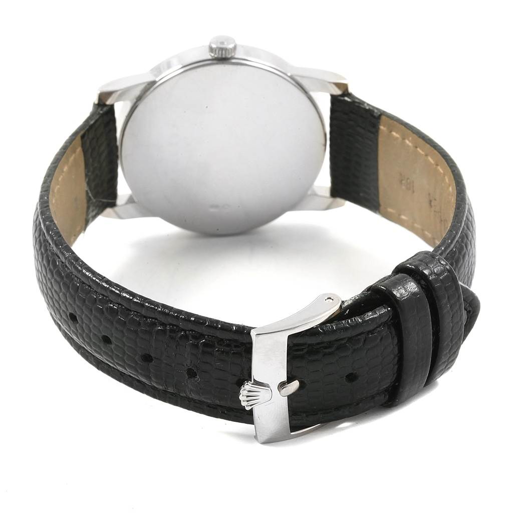 The image shows the back of a Rolex Cellini 5116 Men's White Gold Silver Dial 5116 Men's White Gold Silver Dial watch and its black leather strap with a buckle.