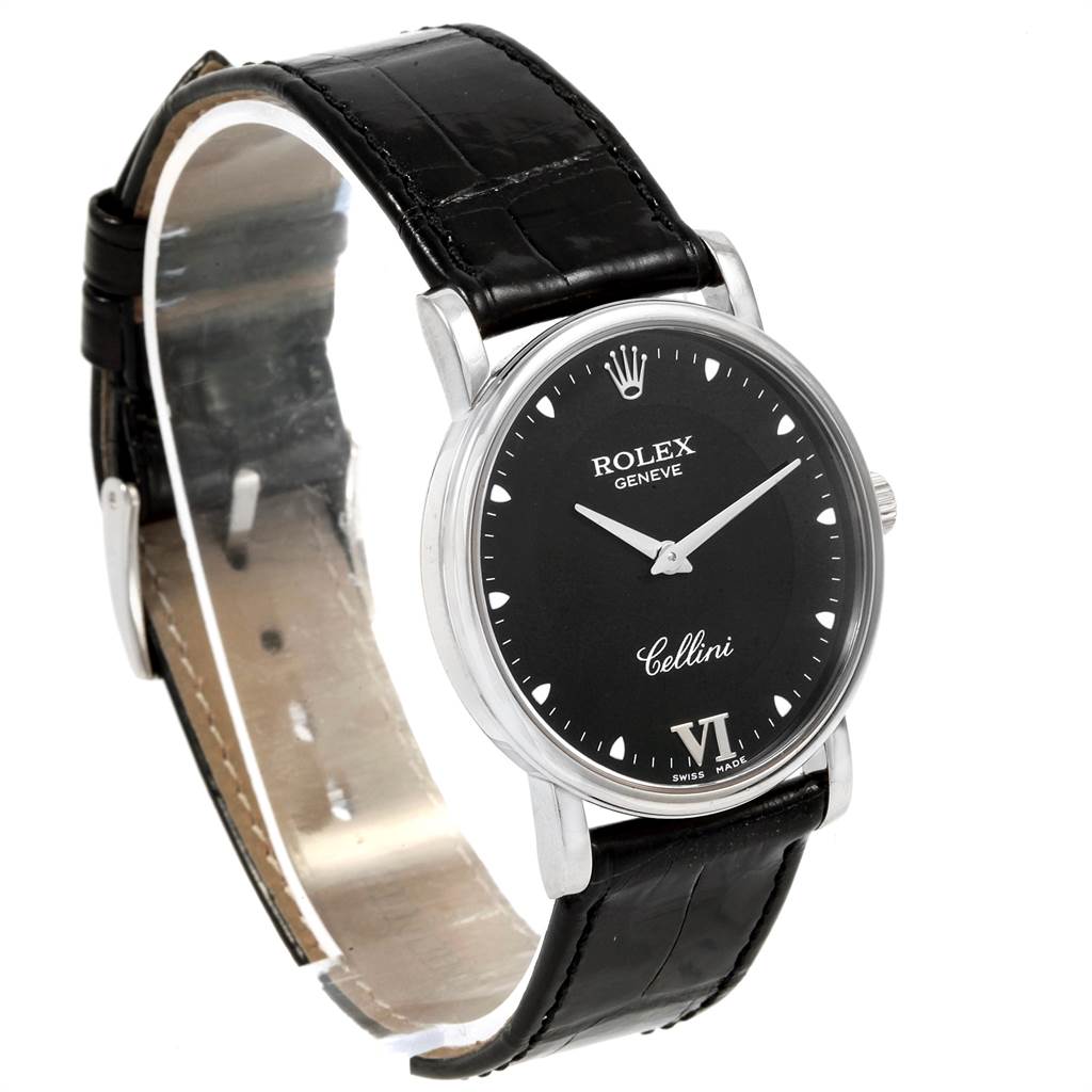 The watch is a Rolex Cellini 5115 Men's White Gold Black Dial 5115 Men's White Gold Black Dial model shown at a slight angle, displaying its black dial, silver case, and black leather strap.