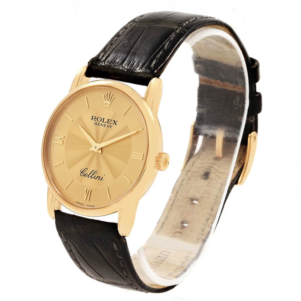 The Rolex Cellini 5116 Men's Yellow Gold Champagne Dial 5116 Men's Yellow Gold Champagne Dial watch is shown at a slight angle, highlighting its gold case, black leather strap, and face with Roman numerals.