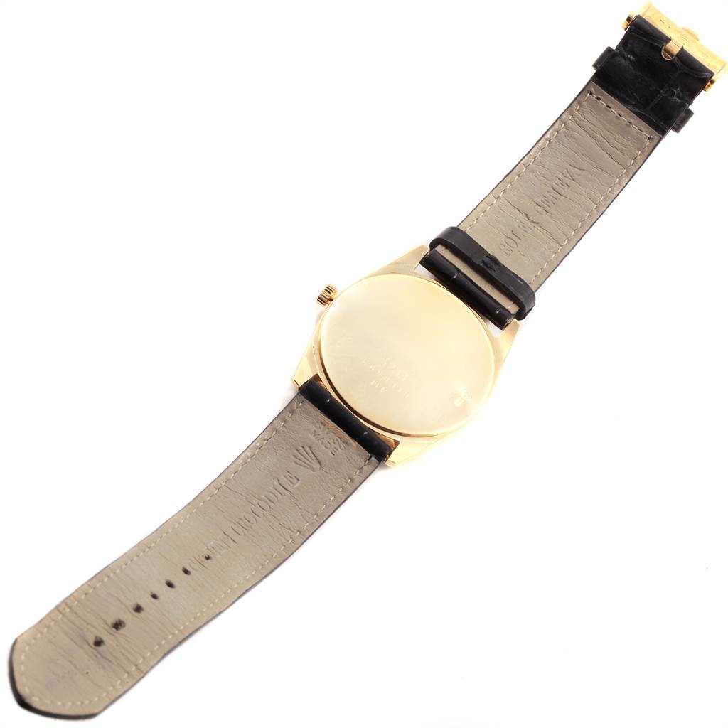 The image shows the back view of a Rolex Cellini 4233 Men's Yellow Gold White Dial 4233 Men's Yellow Gold White Dial watch, including its leather strap and gold case.