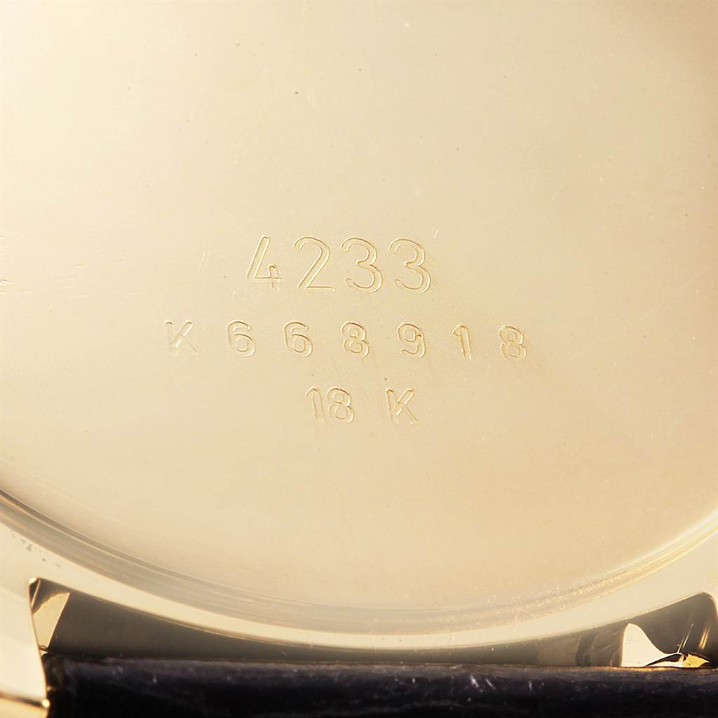 The image shows the gold back cover of a Rolex Cellini 4233 Men's Yellow Gold White Dial 4233 Men's Yellow Gold White Dial model with engravings for model number, serial number, and 18K gold marking.
