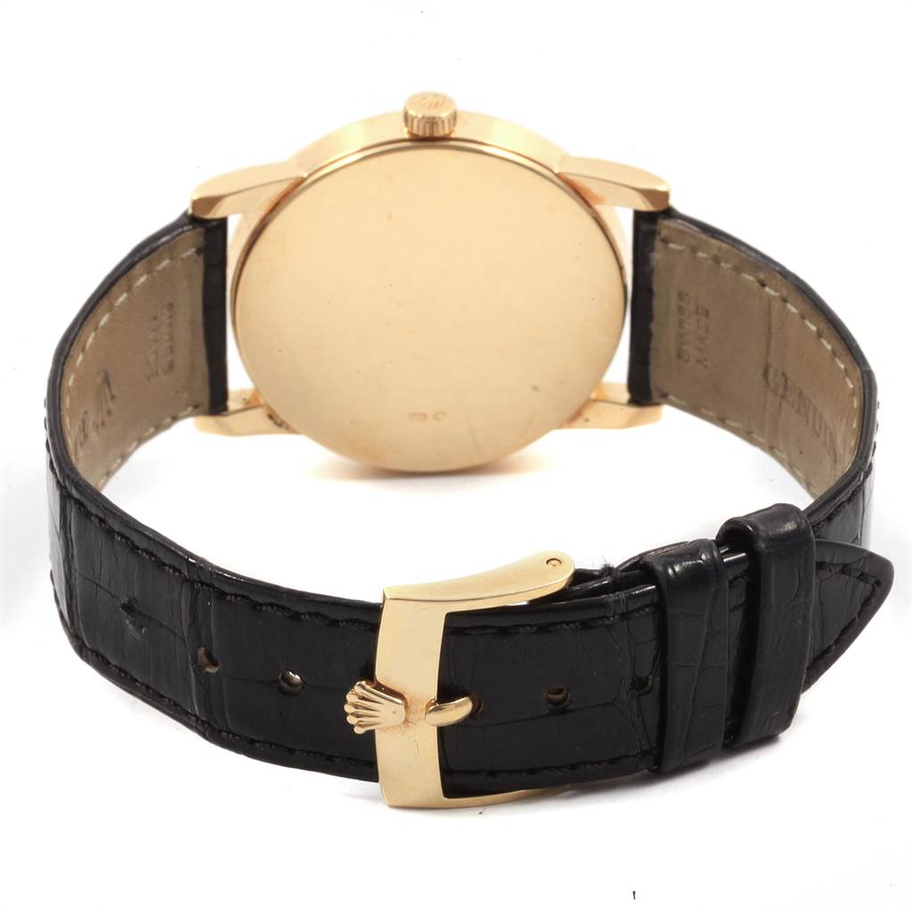 The image shows the back view of a Rolex Cellini 5116 Men's Yellow Gold Grey Dial 5116 Men's Yellow Gold Grey Dial watch, highlighting its gold case, crown, and black leather strap with a gold buckle.