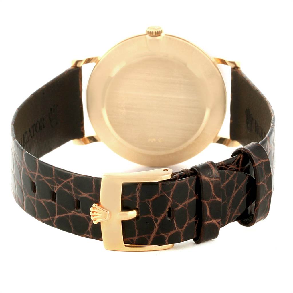 The image shows the back view of a Rolex Cellini 5112 Men's Yellow Gold Beige Dial 5112 Men's Yellow Gold Beige Dial watch, focusing on its gold case and patterned leather strap with a gold buckle.