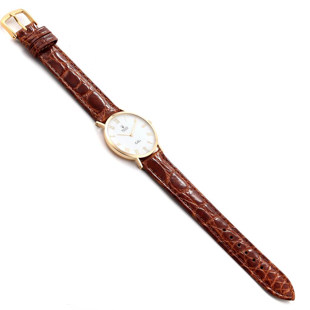 The image shows a full view of a Rolex Cellini 4112 Men
s Yellow Gold White Dial 4112 Men
s Yellow Gold White Dial watch with a brown leather strap and a gold case, lying flat on a white surface.