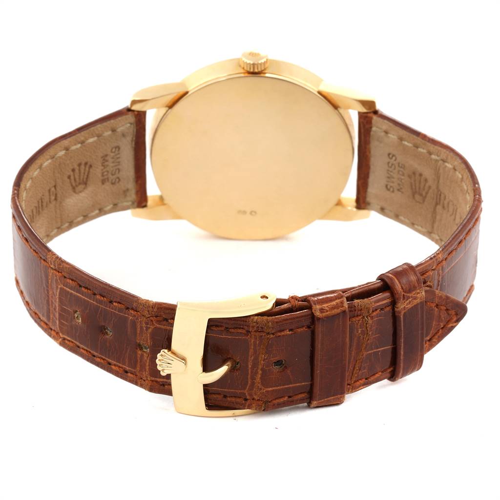 The image shows the back view of a Rolex Cellini 5116 Men's Yellow Gold Champagne Dial 5116 Men's Yellow Gold Champagne Dial watch, highlighting its case back, crown, brown leather strap, and gold buckle.