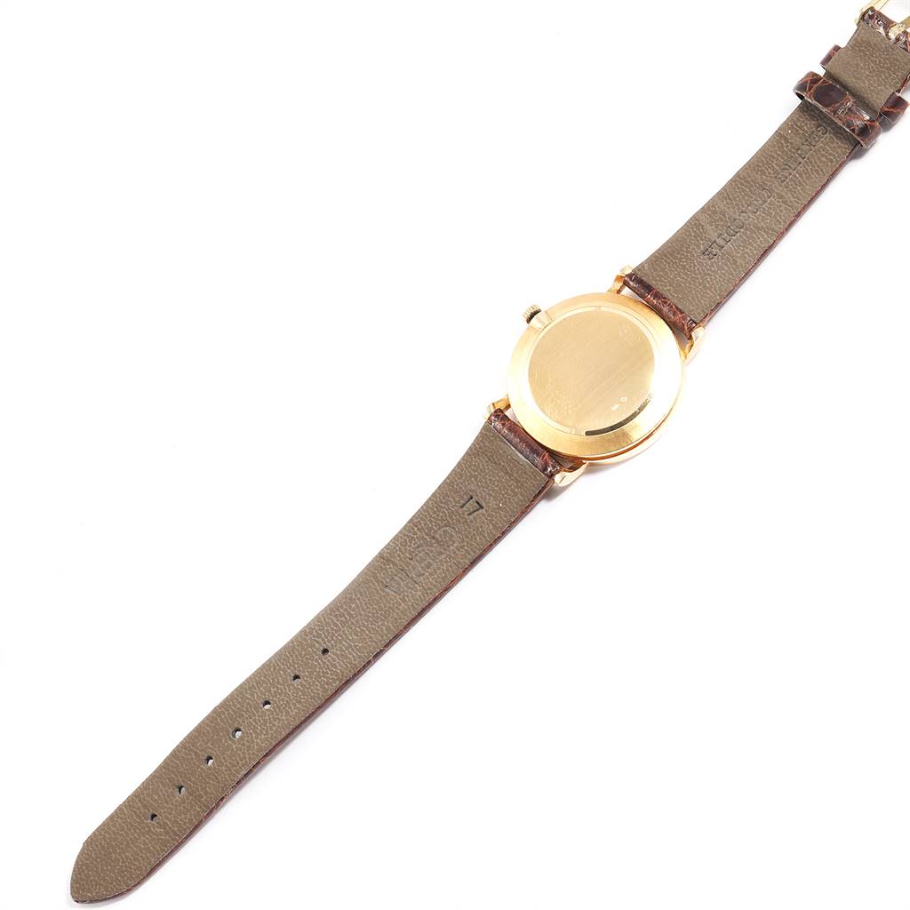 The image shows the back view of a Rolex Cellini 5112 Men's Yellow Gold Champagne Dial 5112 Men's Yellow Gold Champagne Dial watch, including its gold case and leather strap.