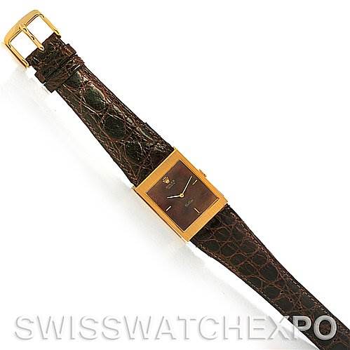 The image shows a top-down view of a Rolex Cellini 4127 Men's Yellow Gold Brown Dial 4127 Men's Yellow Gold Brown Dial model watch with a brown leather strap and a rectangular gold frame.