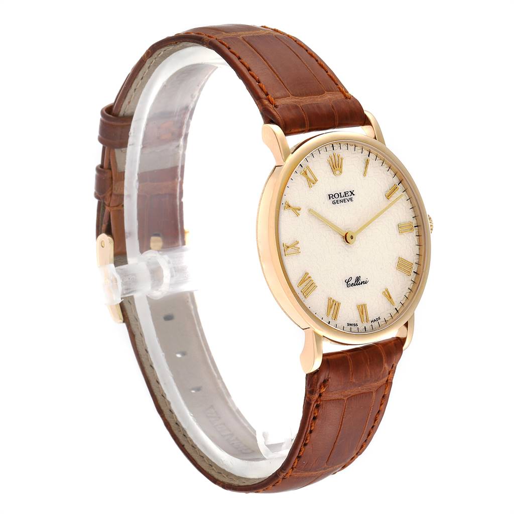 The Rolex Cellini 5112 Men's Yellow Gold Beige Dial 5112 Men's Yellow Gold Beige Dial watch is shown at a three-quarter angle, displaying its brown leather strap, white dial with Roman numerals, and gold case.