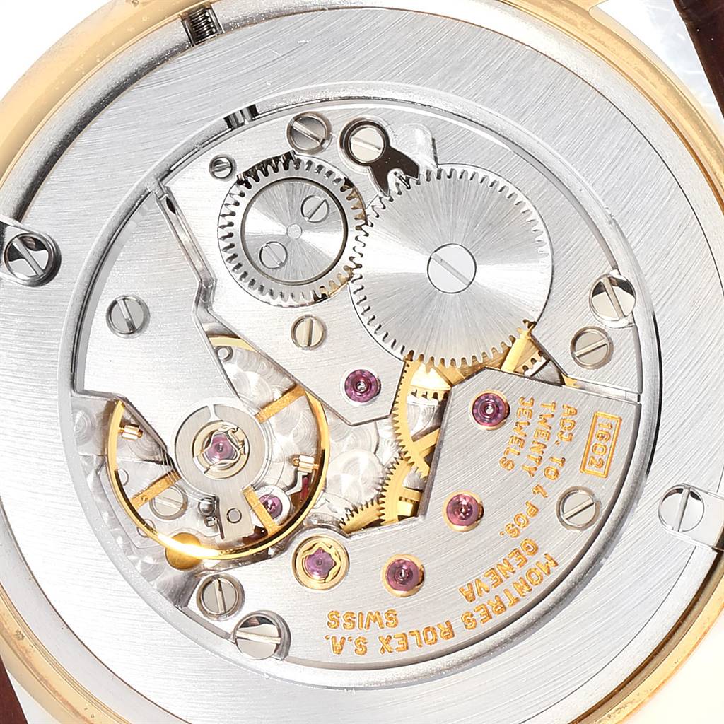The image shows a close-up of the internal mechanism of a Rolex Cellini 5116 Men's Yellow Gold Silver Dial 5116 Men's Yellow Gold Silver Dial watch, highlighting the gears and movement components.