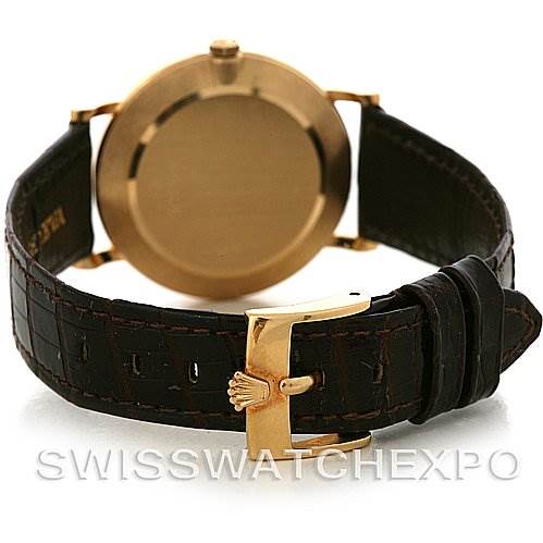 The image shows the back view of a Rolex Cellini 5112 Men's Yellow Gold White Dial 5112 Men's Yellow Gold White Dial watch, including its gold case and dark leather strap with a gold clasp.