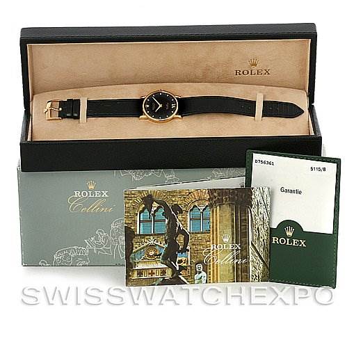 The image shows a Rolex Cellini 5115 Men's Yellow Gold Black Dial 5115 Men's Yellow Gold Black Dial watch with a black strap, displayed in its open box, alongside its guarantee card and booklet.