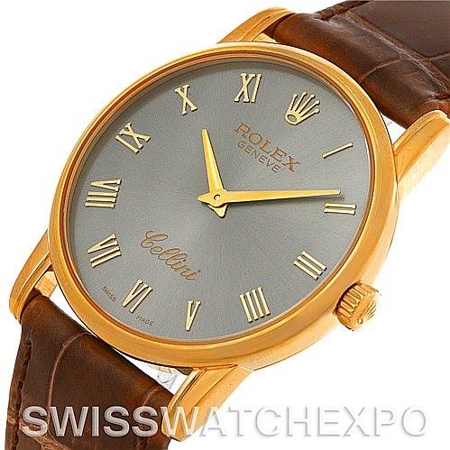 The image shows a close-up, angled view of the Rolex Cellini 5116 Men's Yellow Gold Grey Dial 5116 Men's Yellow Gold Grey Dial watch, highlighting its face, gold casing, crown, and part of the leather strap.