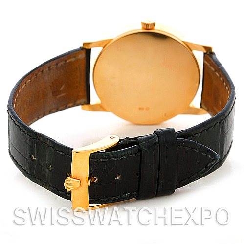 The image shows the back of a Rolex Cellini 5116 Men's Yellow Gold Silver Dial 5116 Men's Yellow Gold Silver Dial watch with a gold case and a black leather strap with a gold buckle.