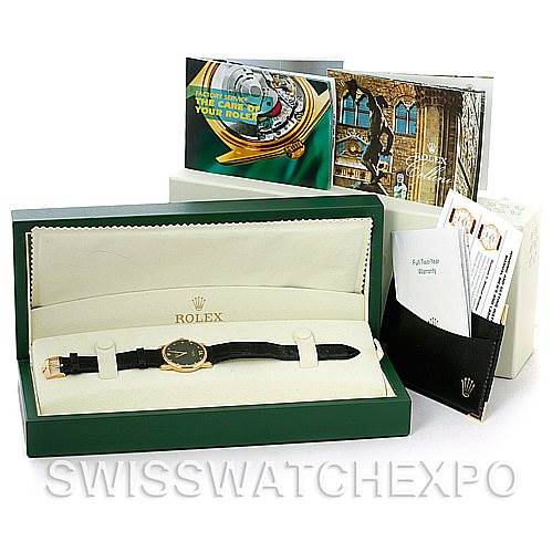 The image shows a Rolex Cellini 5116 Men's Yellow Gold Black Dial 5116 Men's Yellow Gold Black Dial watch laid flat inside its open green box, accompanied by booklets and documents.