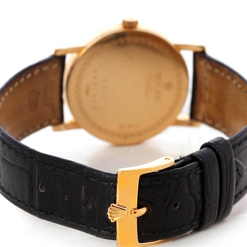 This image shows the back of a Rolex Cellini 5115 Men's Yellow Gold Silver Dial 5115 Men's Yellow Gold Silver Dial watch with its gold case and black leather strap, along with the clasp buckle.