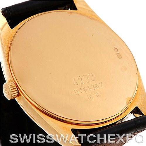 This image shows the back case of a Rolex Cellini 4233 Men's Yellow Gold Black Dial 4233 Men's Yellow Gold Black Dial watch, highlighting its gold finish, inscriptions, and a portion of the black strap.
