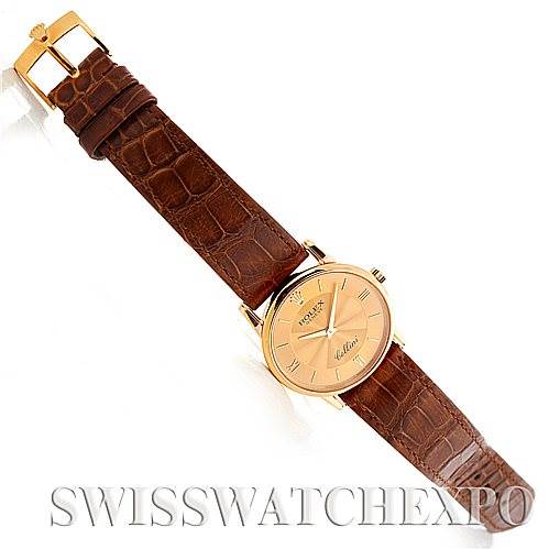 The image shows a top-down view of a Rolex Cellini 5116 Men
s Yellow Gold Champagne Dial 5116 Men
s Yellow Gold Champagne Dial watch with a brown leather strap and a round gold case.