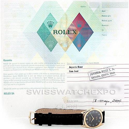 The watch shown is a Rolex Cellini 4233 Men's Yellow Gold Black Dial 4233 Men's Yellow Gold Black Dial model, displayed from a side angle with a black strap, in front of documentation.