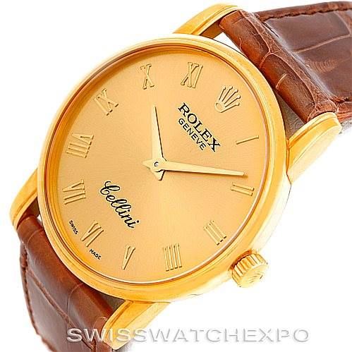 The image shows a close-up angled view of a Rolex Cellini 5116 Men's Yellow Gold Champagne Dial 5116 Men's Yellow Gold Champagne Dial watch, displaying its gold case, brown leather strap, and Roman numerals on the dial.
