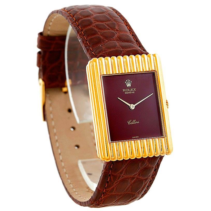 The Rolex Cellini 4016 Men's Yellow Gold Brown Dial 4016 Men's Yellow Gold Brown Dial watch is shown at a slight angle, displaying its brown leather strap, gold rectangular case, and maroon dial.