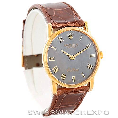 The image shows a three-quarter view of a Rolex Cellini 5116 Men's Yellow Gold Grey Dial 5116 Men's Yellow Gold Grey Dial watch with a gold case, gray dial, Roman numeral hour markers, and brown leather strap.