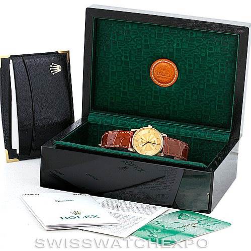 This image shows a Rolex Cellini 5116 Men's Yellow Gold Champagne Dial 5116 Men's Yellow Gold Champagne Dial watch placed inside its open box, accompanied by a booklet, warranty card, and black holder.