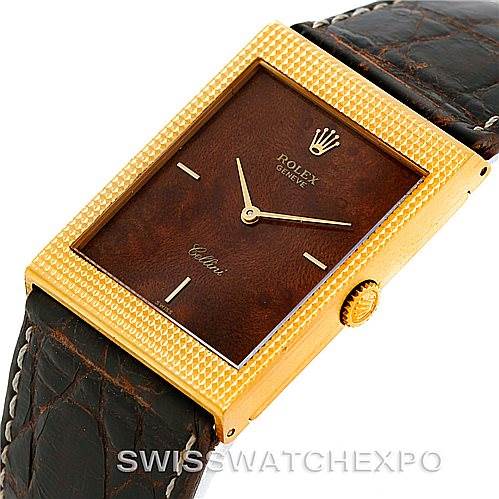 The image shows a Rolex Cellini 4127 Men
s Yellow Gold Brown Dial 4127 Men
s Yellow Gold Brown Dial watch from an angled top-down perspective, highlighting its gold rectangular case, brown dial, and leather strap.
