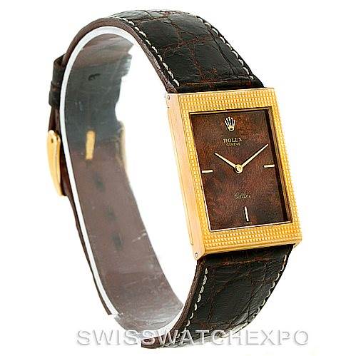 The image shows a Rolex Cellini 4127 Men
s Yellow Gold Brown Dial 4127 Men
s Yellow Gold Brown Dial model watch at a side-angle view, highlighting its rectangular face, brown dial, and leather strap.