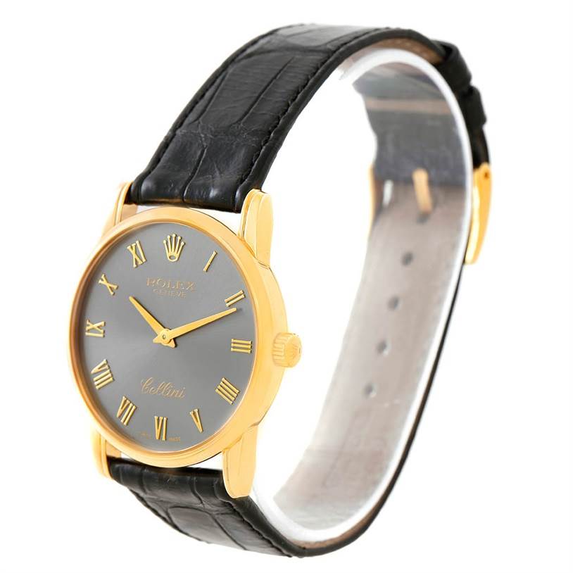 The Rolex Cellini 5116 Men's Yellow Gold Grey Dial 5116 Men's Yellow Gold Grey Dial watch is shown at a slight angle, featuring its gold case, black leather strap, and grey dial with Roman numerals.