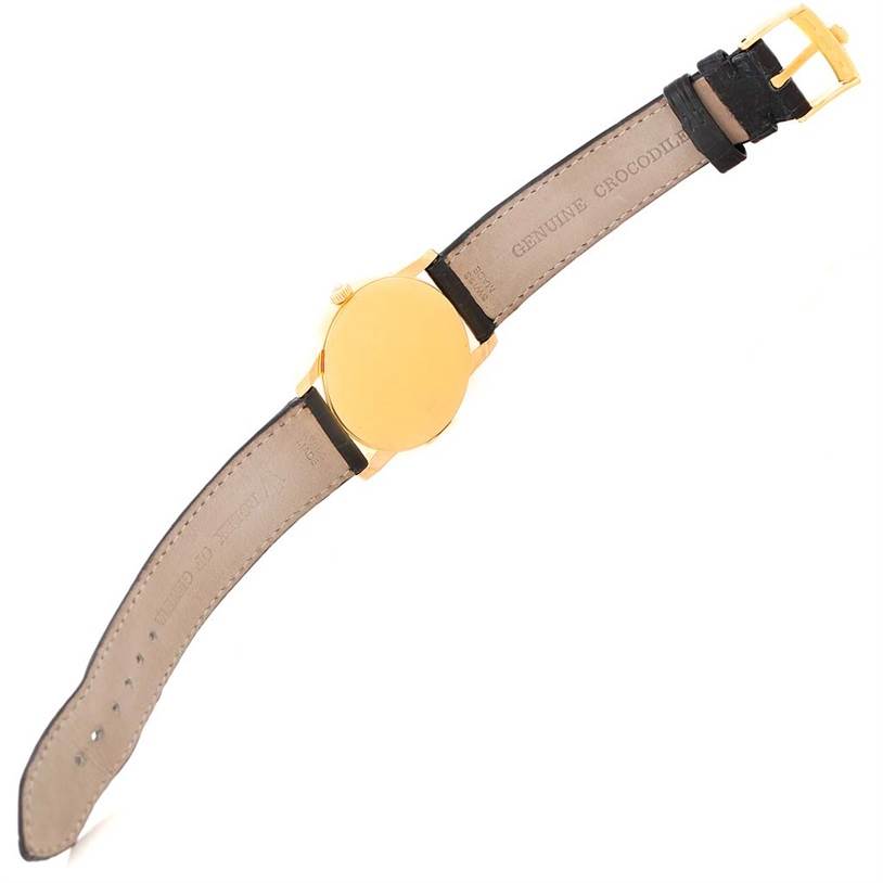 The image shows the back of a Rolex Cellini 5116 Men's Yellow Gold Grey Dial 5116 Men's Yellow Gold Grey Dial watch, featuring its gold case and crocodile leather strap with a buckle.