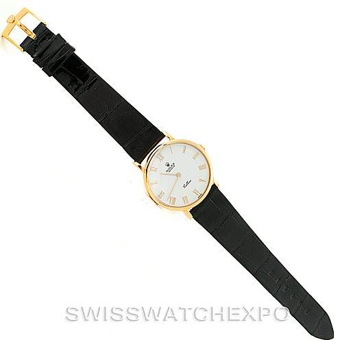 The Rolex Cellini 5112 Men's Yellow Gold White Dial 5112 Men's Yellow Gold White Dial watch is shown from a top-down angle, displaying its round gold case, white dial, black leather strap, and gold buckle.