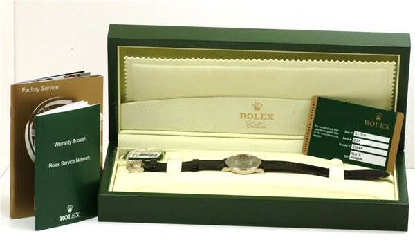 The Rolex Cellini 5115/9 Men
s White Gold Grey Dial 5115/9 Men
s White Gold Grey Dial watch is shown from a top-down angle with its box, warranty card, and booklets included.