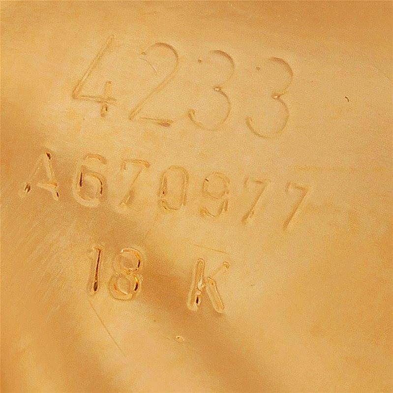 The image shows a close-up of the Rolex Cellini 4233 Men's Yellow Gold White Dial 4233 Men's Yellow Gold White Dial model's case back, featuring engraved model and serial numbers and an 18K gold mark.