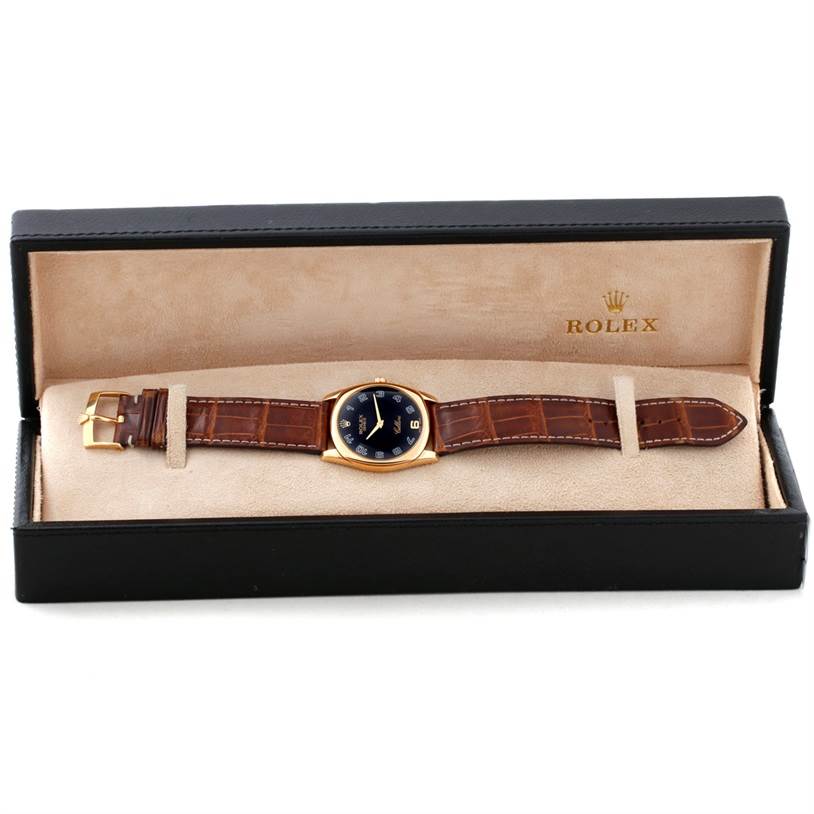 The image shows a Cellini model by Rolex lying flat in its open display box, showcasing the watch face and leather strap.