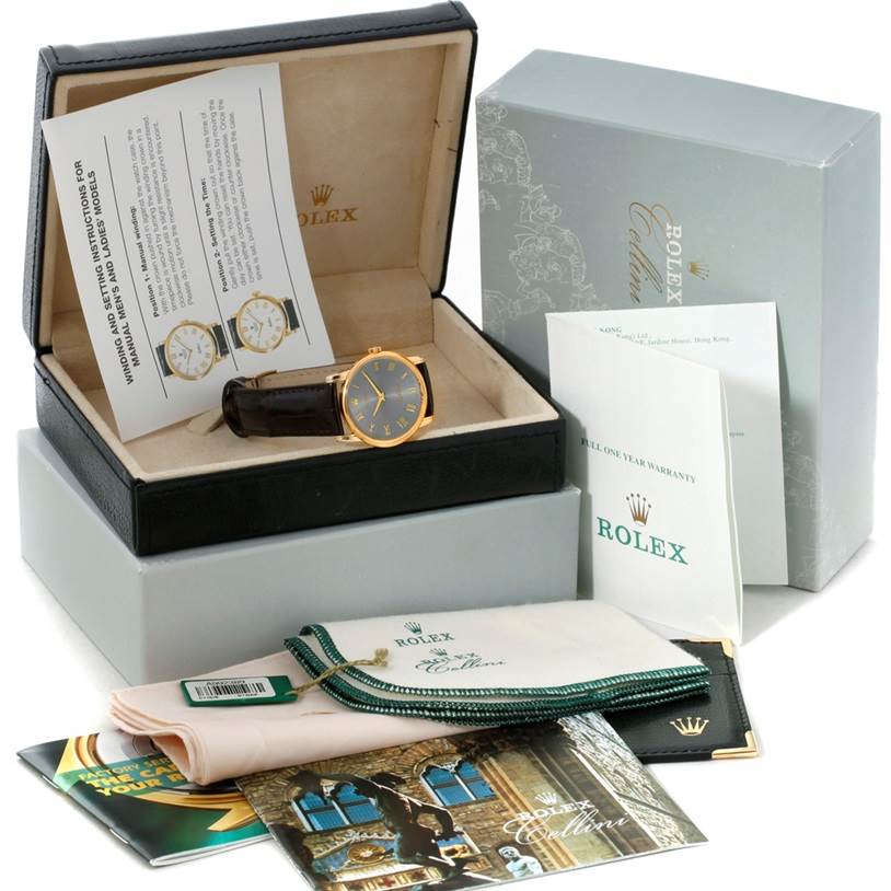 The image shows the Rolex Cellini 5116 Men's Yellow Gold Grey Dial 5116 Men's Yellow Gold Grey Dial watch with its box, warranty card, manual, and cleaning cloths, viewed from the front.