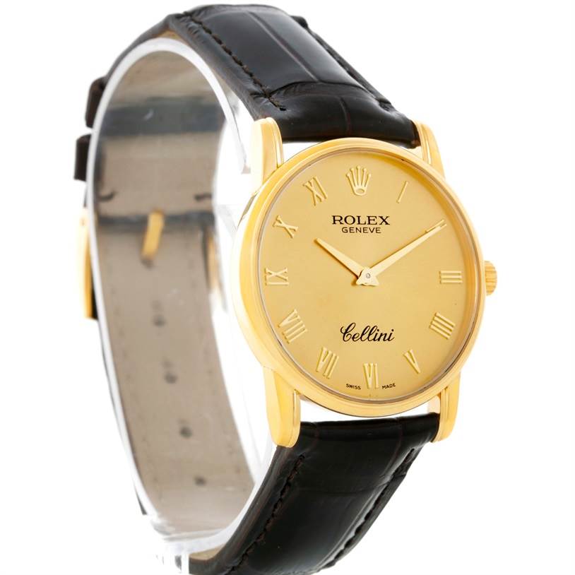 The image shows a Rolex Cellini 5116 Men
s Yellow Gold Champagne Dial 5116 Men
s Yellow Gold Champagne Dial watch from an angled side view, showcasing its gold case, black leather strap, and dial with Roman numerals.