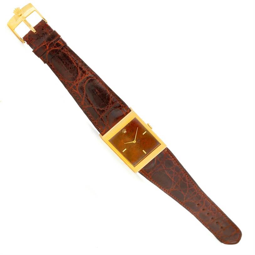 The image shows a Rolex Cellini 4127 Men's Yellow Gold Brown Dial 4127 Men's Yellow Gold Brown Dial watch from a top-down angle, displaying its brown leather strap, rectangular gold case, and dial.