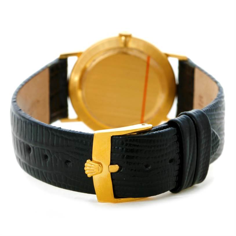 The image shows the back of a Rolex Cellini 3833 Men
s Yellow Gold Champagne Dial 3833 Men
s Yellow Gold Champagne Dial watch, focusing on its black leather strap and gold buckle with the Rolex logo.