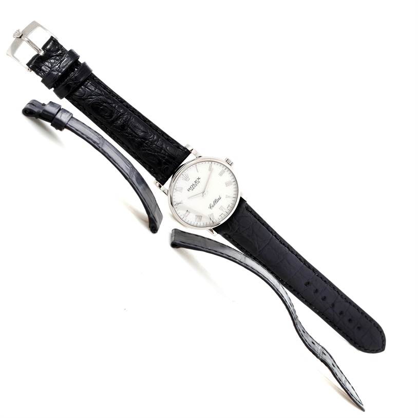 The Rolex Cellini 5116 Men's White Gold Silver Dial 5116 Men's White Gold Silver Dial watch is shown at a top-down angle with black leather straps detached alongside it.