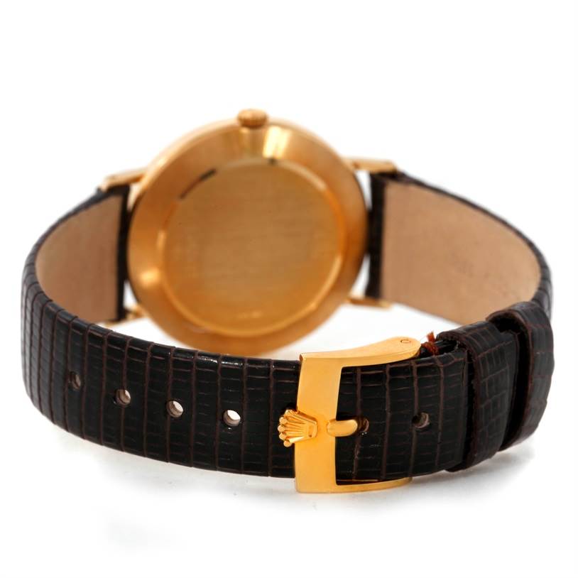 The Rolex Cellini 4112 Yellow Gold Champagne Dial 4112 Yellow Gold Champagne Dial watch is shown from the back, displaying its gold case and a black leather strap with a gold buckle.