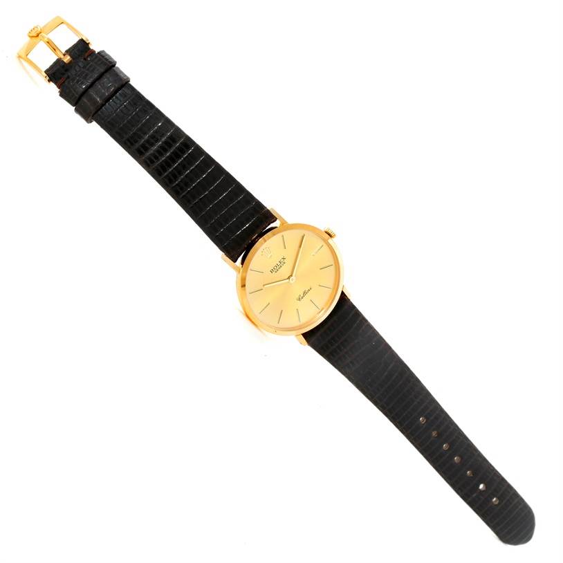 The watch, a Rolex Cellini 4112 Yellow Gold Champagne Dial 4112 Yellow Gold Champagne Dial model, is shown from a top-down angle, displaying its black strap and gold face.