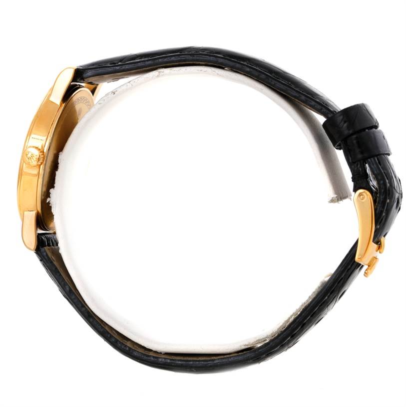 The Rolex Cellini 5115 Men
s Yellow Gold Black Dial 5115 Men
s Yellow Gold Black Dial watch is shown in a side profile view, highlighting its gold case, crown, and black leather strap with buckle.