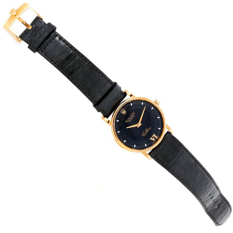 This image shows a Rolex Cellini 5115 Men's Yellow Gold Black Dial 5115 Men's Yellow Gold Black Dial watch from a top-down angle, highlighting its black leather strap, gold case, and black dial.