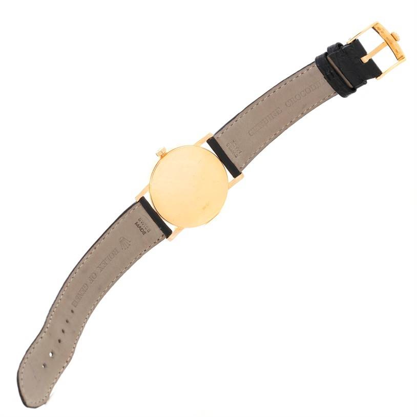 The image shows the back side of a Rolex Cellini 5115 Men's Yellow Gold Black Dial 5115 Men's Yellow Gold Black Dial watch, displaying the leather strap and gold casing.