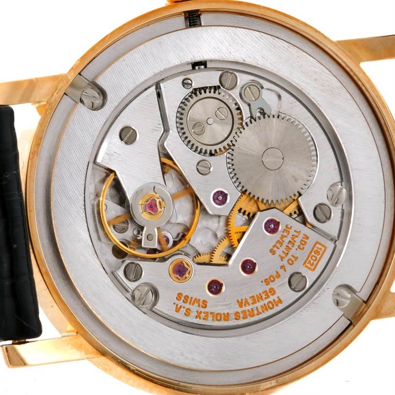 The image shows a close-up of the movement and inner workings of a Rolex Cellini 5115 Men's Yellow Gold Black Dial 5115 Men's Yellow Gold Black Dial watch.